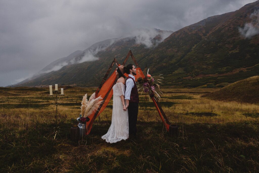 A couple stands in front of the altar at their intimate wedding location in the Chugach Mountains in Alaska.