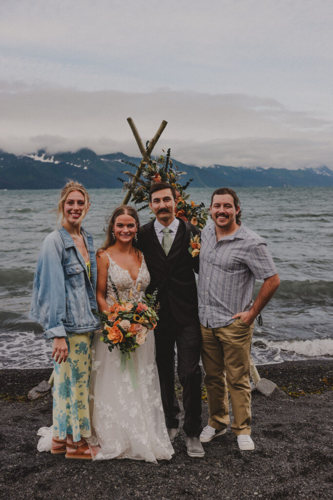 The bride and groom stand with their good friends from out of Alaska after eloping on a beach in Seward.